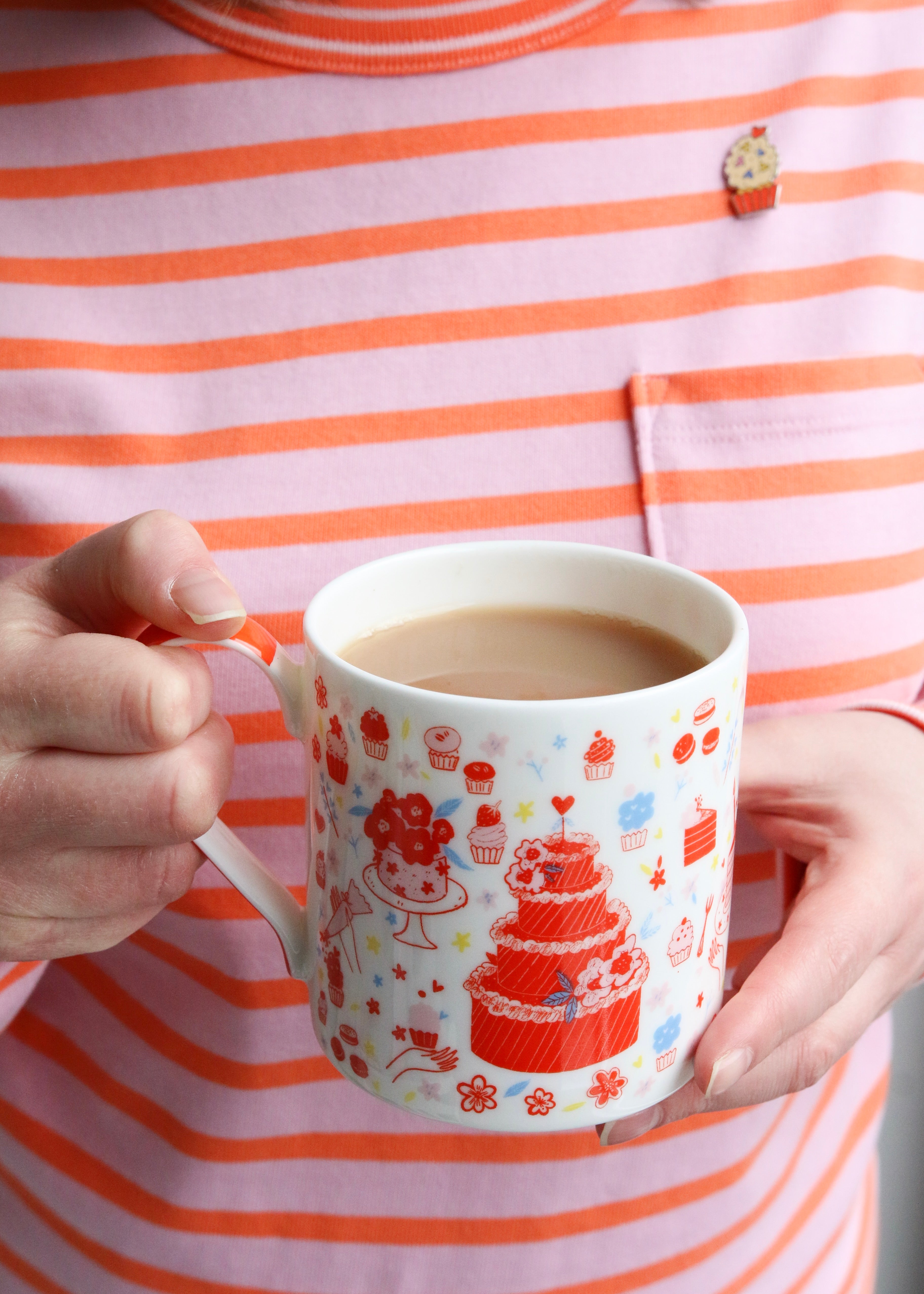 Holding Illustrated Mug Featuring Cake & Cupcakes with Orange Handle