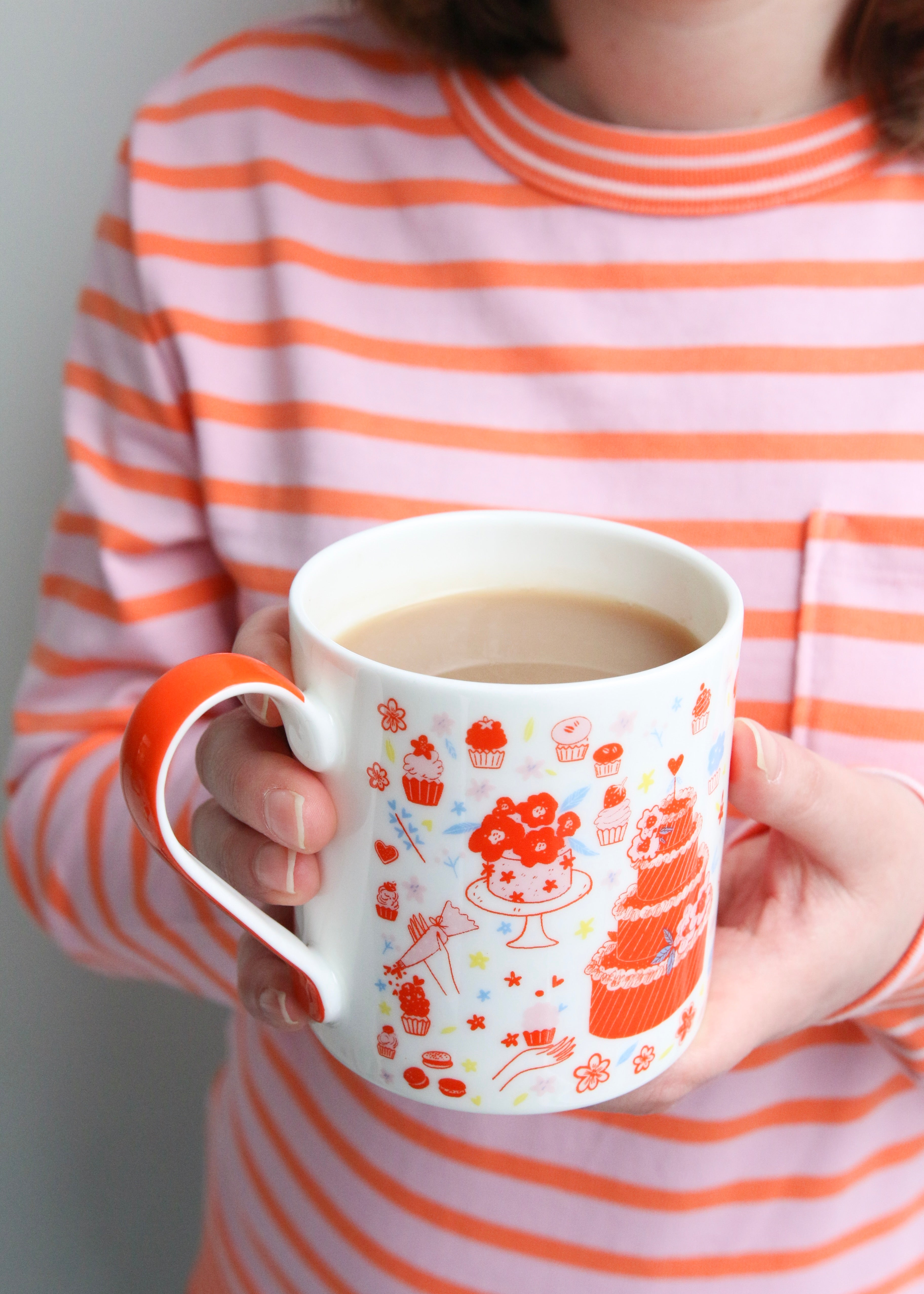 Illustrated Mug Featuring Cake & Cupcakes with Orange Handle Held with Tea