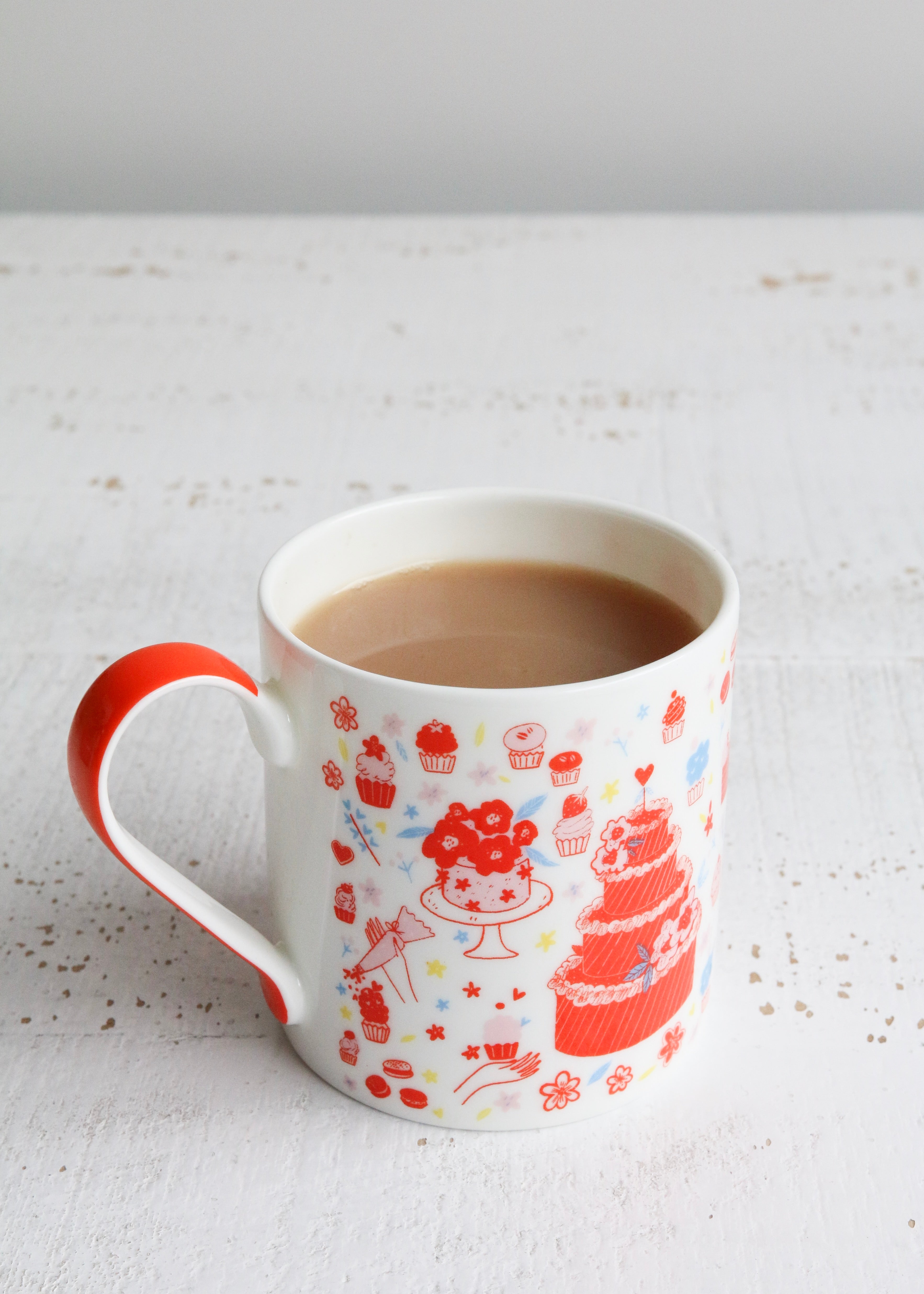 Illustrated Mug Featuring Cake & Cupcakes with Orange Handle on Table