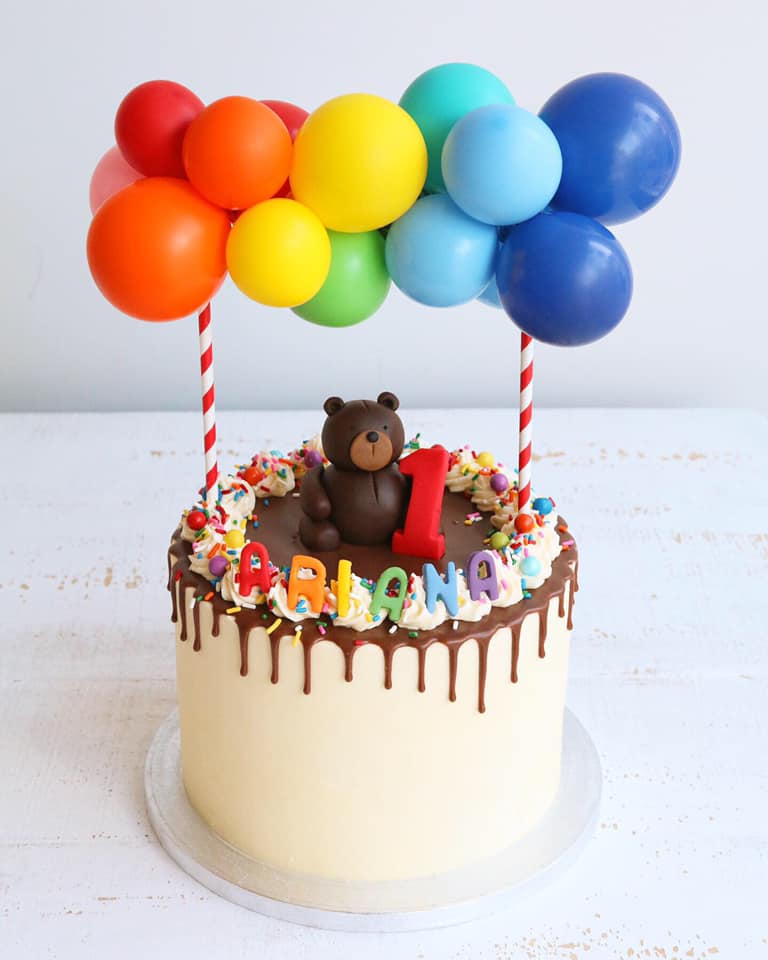 1st Birthday Drip Cake with Rainbow Balloons and a Teddy Holding a Red Number 1