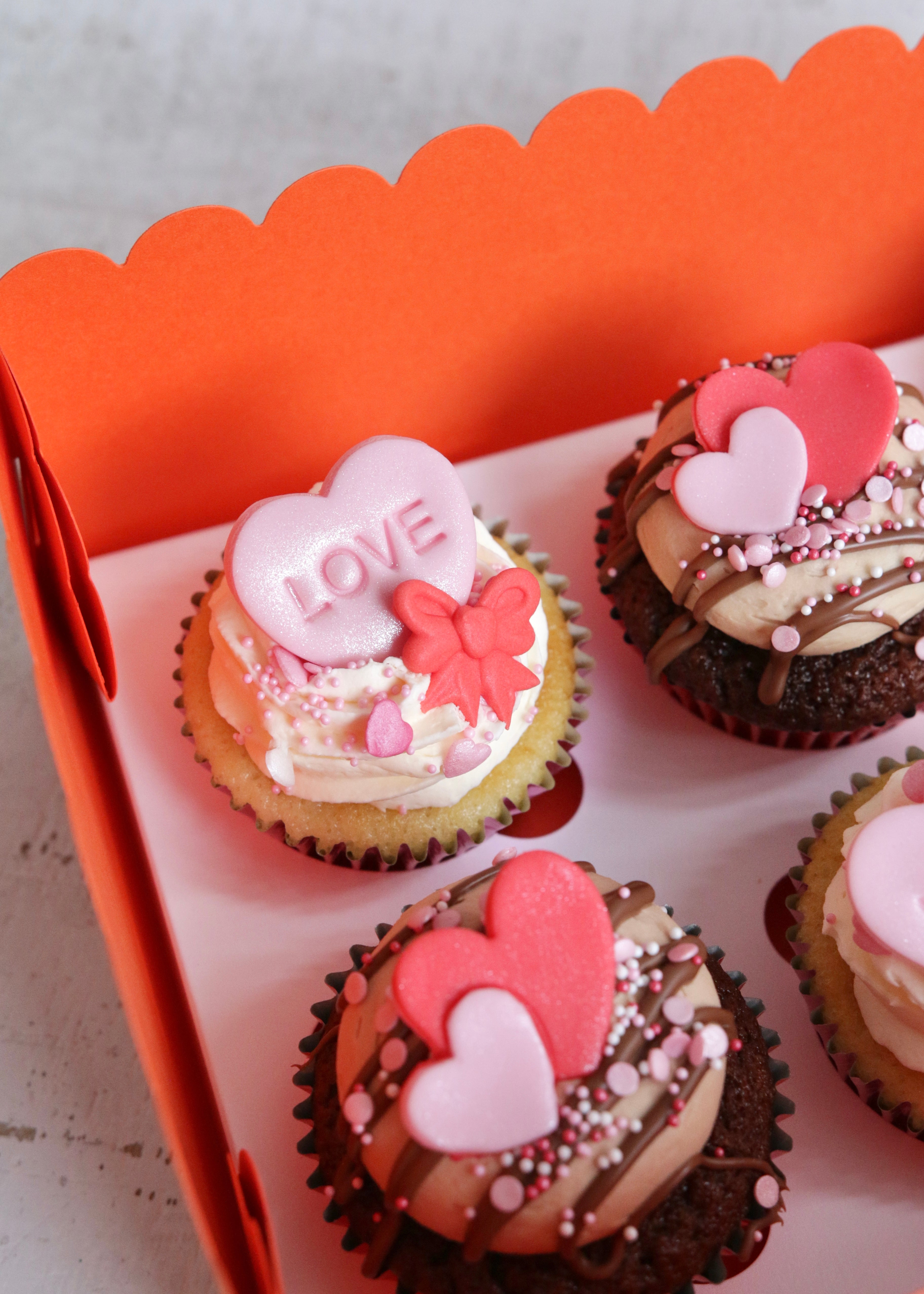 Close Up on Vanilla Valentine's Cupcake in Box with Pink Love Heart & Red Bow Decoration