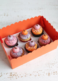 Box of Halloween cupcakes topped with pastel pink, orange and purple buttercream and fondant pumpkins