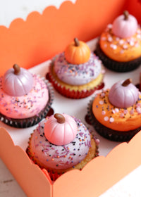Close up on Halloween cupcakes topped with pastel pink, orange and purple buttercream and fondant pumpkins