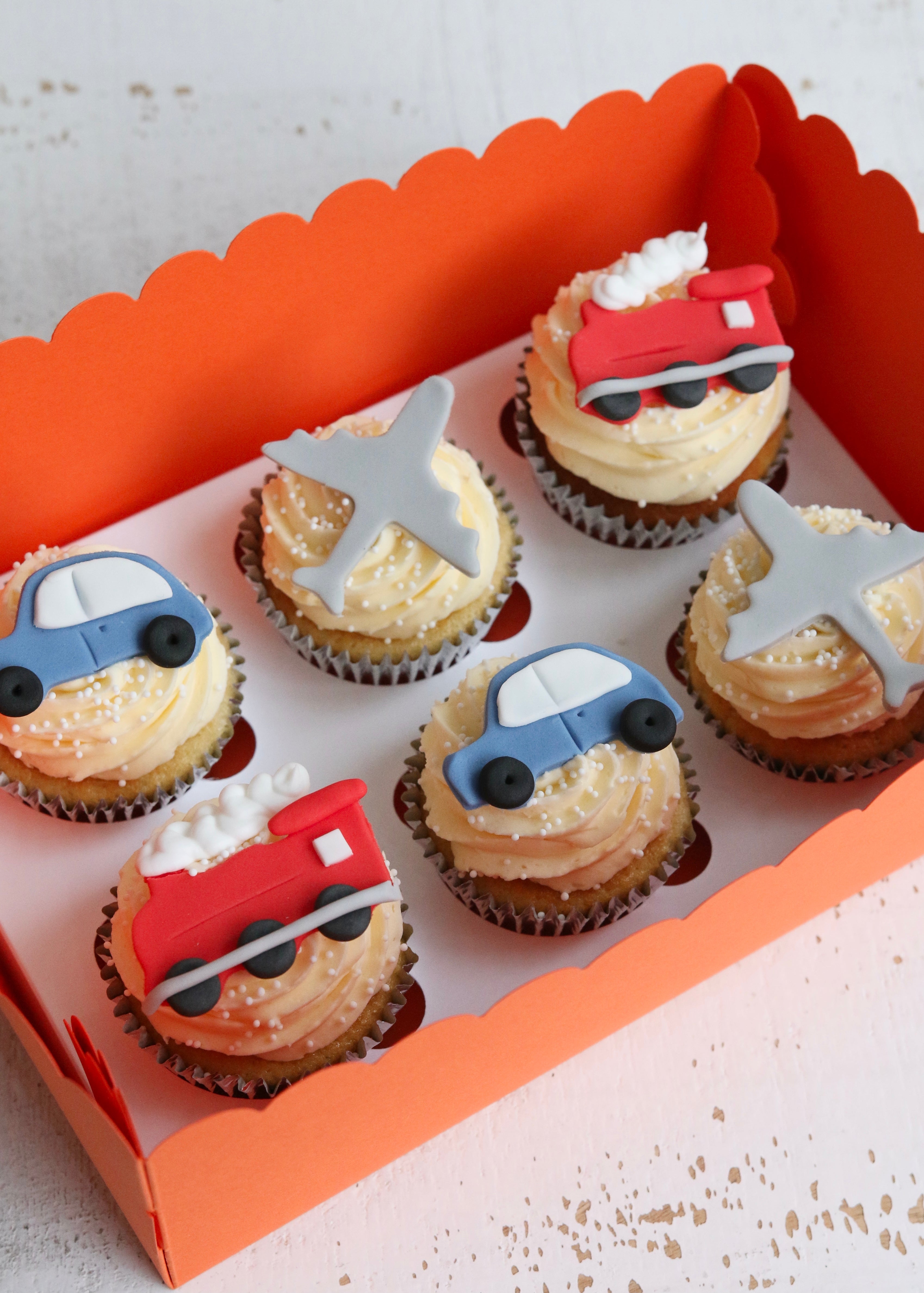 Cupcakes with fondant blue car, plane and red train decorations