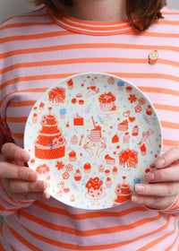Holding Illustrated Plate Featuring Cake & Cupcakes