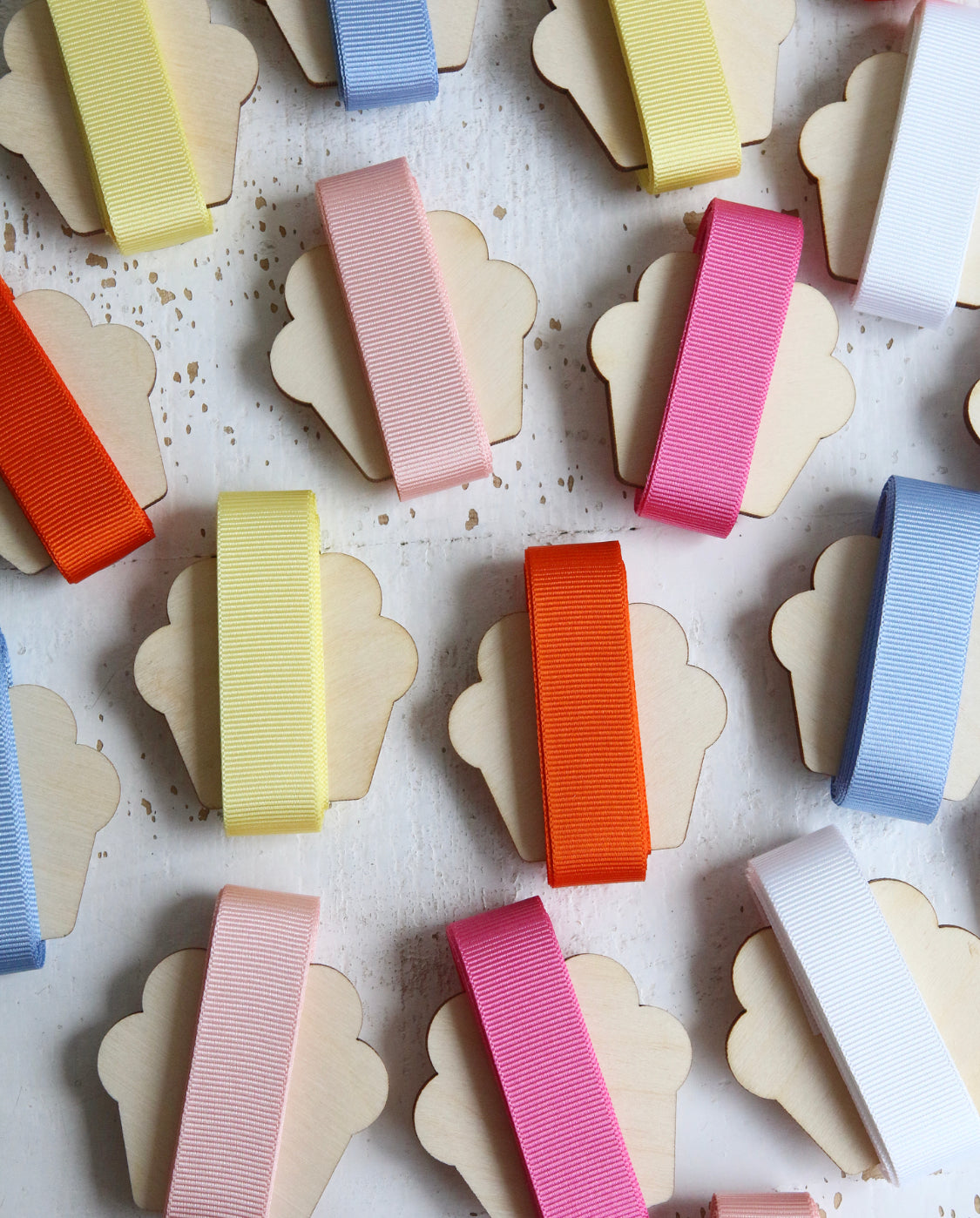 Different coloured grosgrain ribbons wrapped on wooden cutout cupcakes